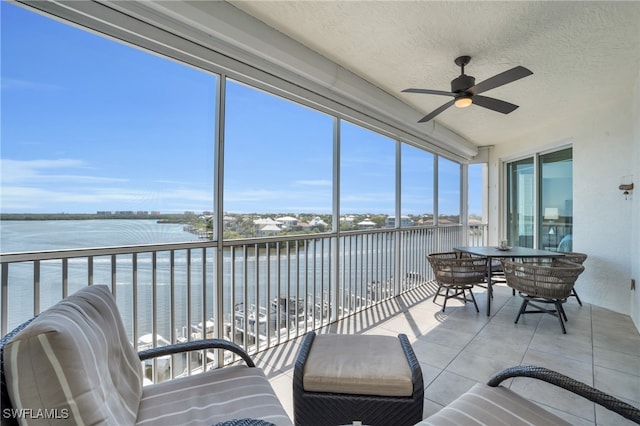 sunroom / solarium featuring a water view and ceiling fan