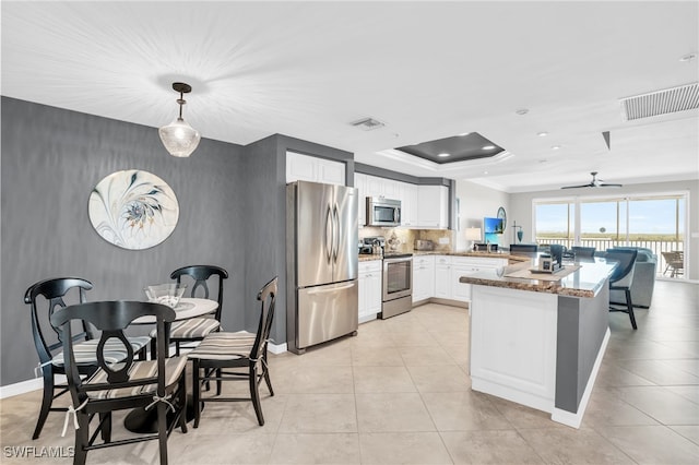 kitchen featuring kitchen peninsula, white cabinets, stone countertops, range, and fridge