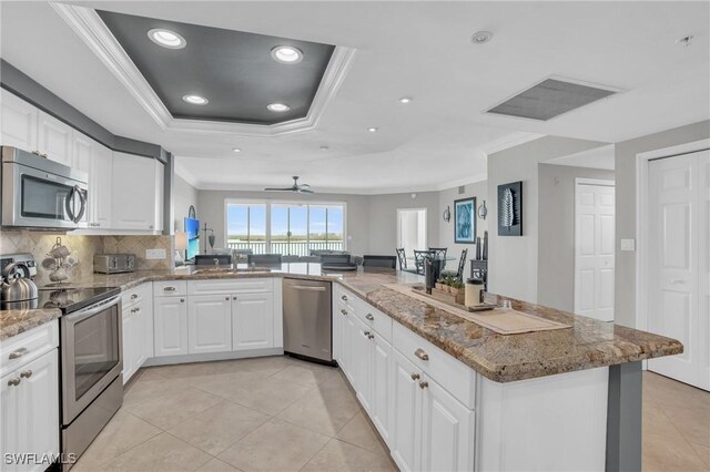 kitchen featuring appliances with stainless steel finishes, kitchen peninsula, light tile patterned flooring, and light stone countertops