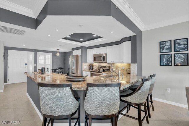 kitchen with appliances with stainless steel finishes, kitchen peninsula, white cabinets, and light tile patterned floors