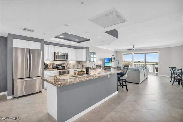 kitchen featuring light tile patterned flooring, stainless steel appliances, light stone countertops, ceiling fan, and white cabinets