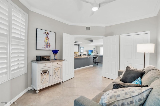 living area with ornamental molding, light tile patterned flooring, visible vents, and baseboards