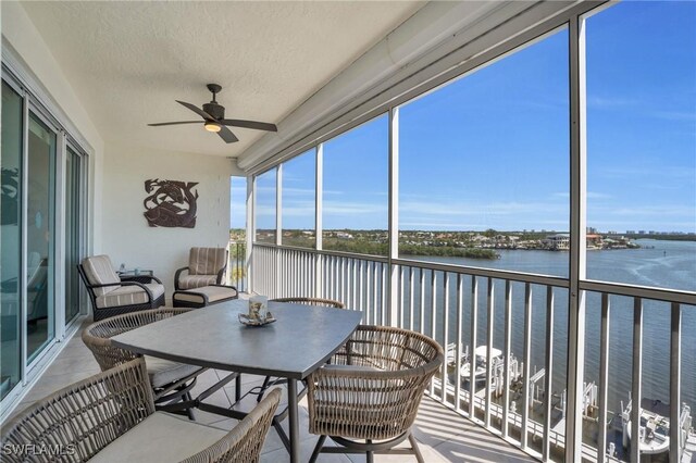 sunroom featuring a water view and ceiling fan