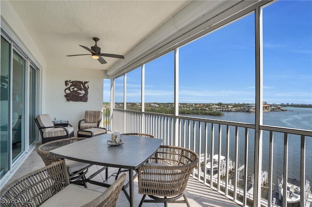 sunroom / solarium with a ceiling fan and a water view