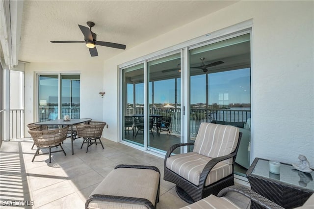 balcony featuring a patio area, outdoor dining area, a ceiling fan, and a sunroom