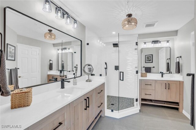 bathroom featuring a shower with door, dual vanity, and tile patterned floors