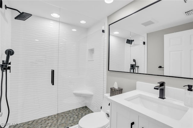 bathroom featuring a shower with shower door, vanity, and toilet