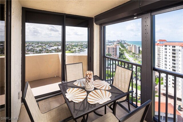 sunroom featuring a water view and a city view