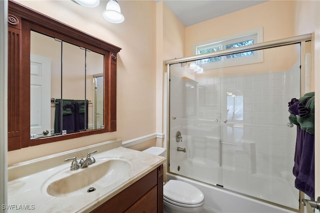 bathroom featuring combined bath / shower with glass door, vanity, and toilet