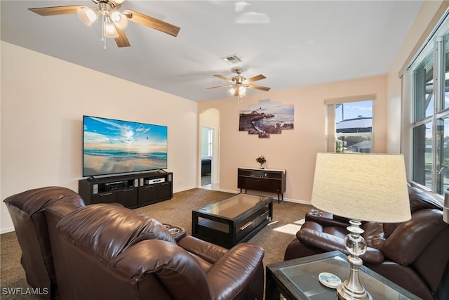 living area featuring arched walkways, dark colored carpet, visible vents, and baseboards