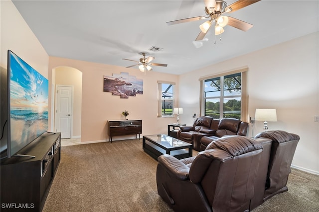 living area featuring arched walkways, visible vents, dark carpet, a ceiling fan, and baseboards