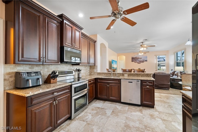 kitchen with tasteful backsplash, arched walkways, open floor plan, stainless steel appliances, and a sink