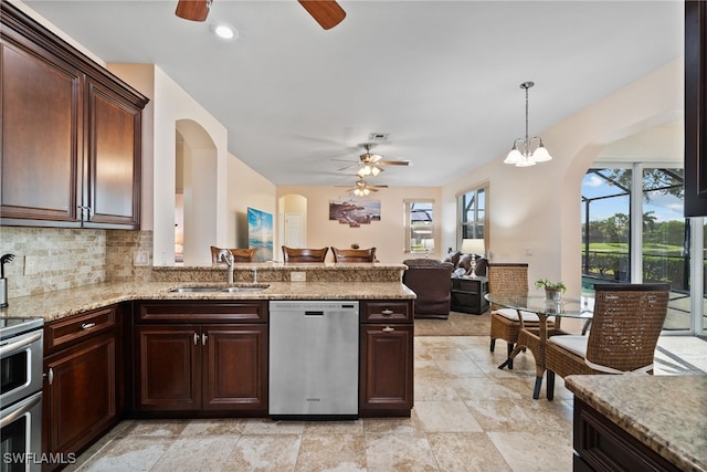 kitchen with tasteful backsplash, open floor plan, stainless steel appliances, pendant lighting, and a sink