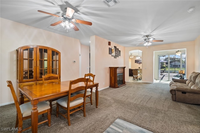 dining room featuring visible vents, arched walkways, baseboards, a glass covered fireplace, and carpet