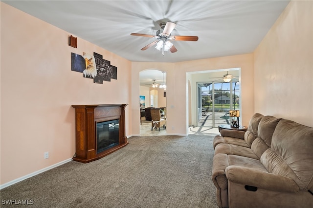 living room with a ceiling fan, a glass covered fireplace, carpet flooring, and baseboards