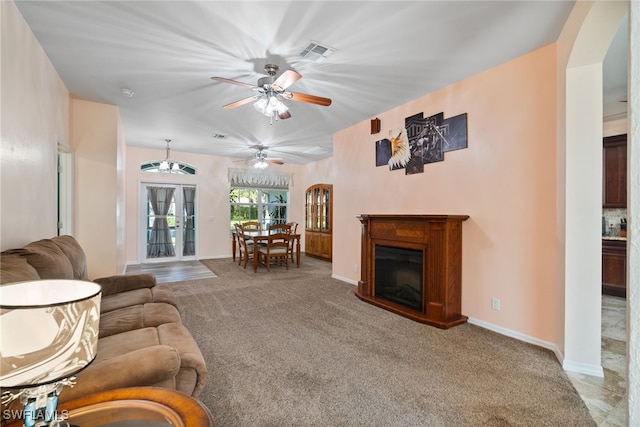 living room with arched walkways, ceiling fan, visible vents, carpet, and a glass covered fireplace