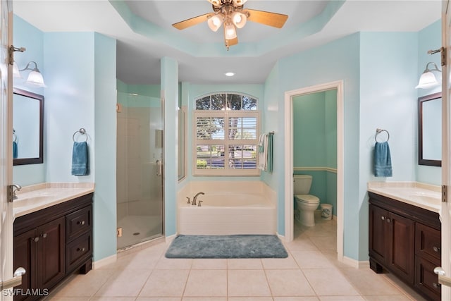 full bath with two vanities, a raised ceiling, a garden tub, and toilet