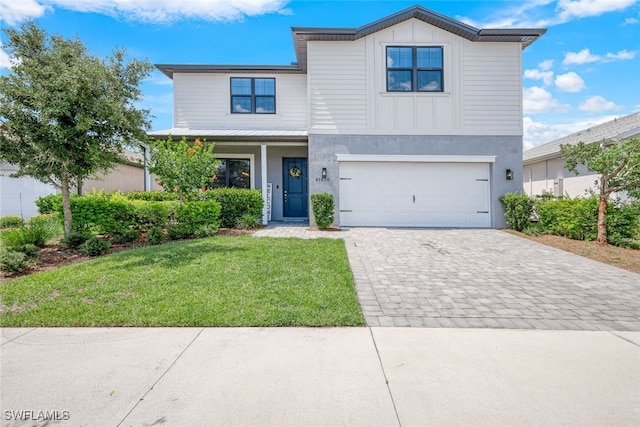 view of front of house with a garage, decorative driveway, a front yard, and board and batten siding