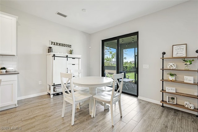 dining room with light wood-type flooring, baseboards, and visible vents