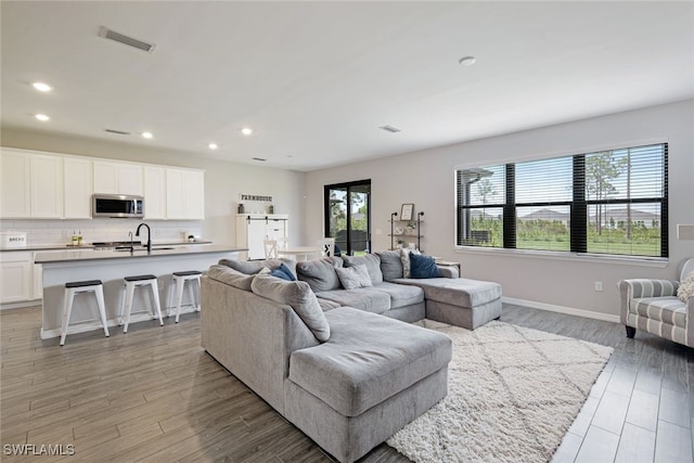 living area featuring recessed lighting, light wood-type flooring, visible vents, and a healthy amount of sunlight