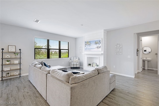 living room featuring visible vents, light wood-style flooring, and baseboards