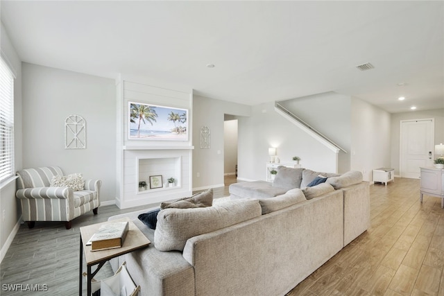 living room with recessed lighting, a fireplace, wood finished floors, visible vents, and baseboards