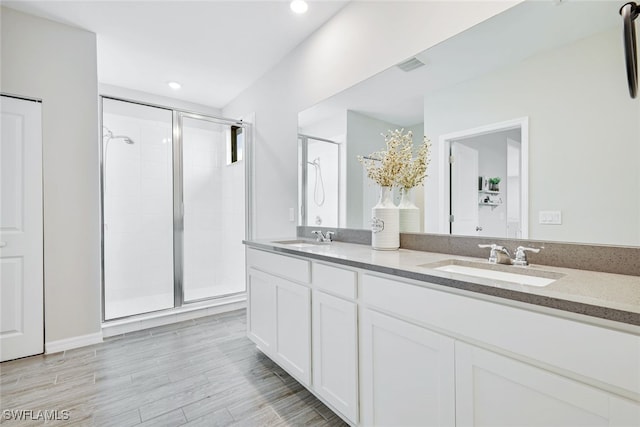 full bathroom with double vanity, wood finished floors, a sink, and visible vents