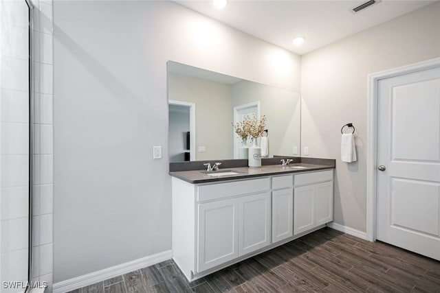 bathroom featuring wood finish floors, visible vents, a sink, and baseboards