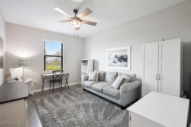 living area featuring baseboards, dark wood finished floors, and a ceiling fan