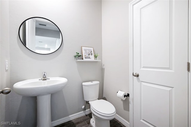 half bath with wood finished floors, toilet, and baseboards