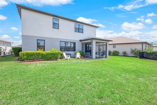 rear view of property featuring a sunroom and a yard