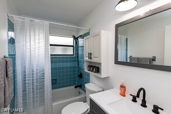 bathroom with shower / bath combo, toilet, and vanity