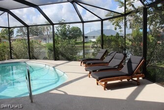 outdoor pool featuring glass enclosure and a patio area