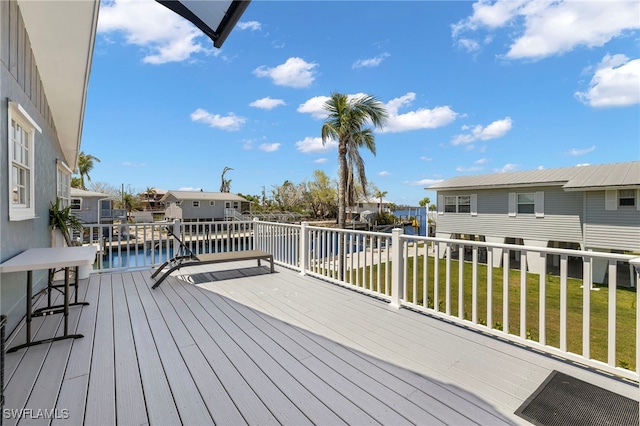 wooden deck with a water view and a lawn