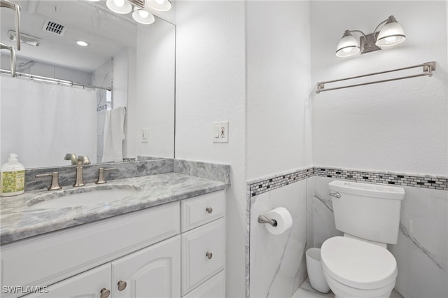 bathroom featuring vanity, curtained shower, tile walls, and toilet