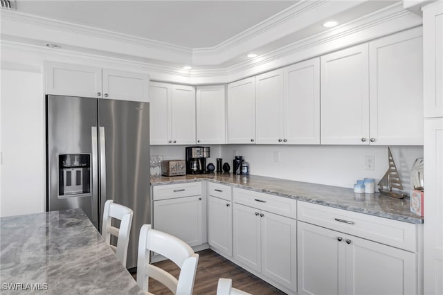 kitchen with stainless steel refrigerator with ice dispenser, dark wood-type flooring, ornamental molding, light stone countertops, and white cabinets