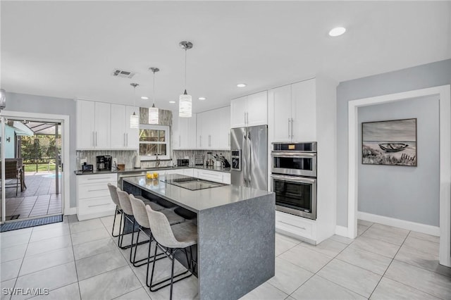 kitchen featuring hanging light fixtures, a center island, white cabinets, and appliances with stainless steel finishes