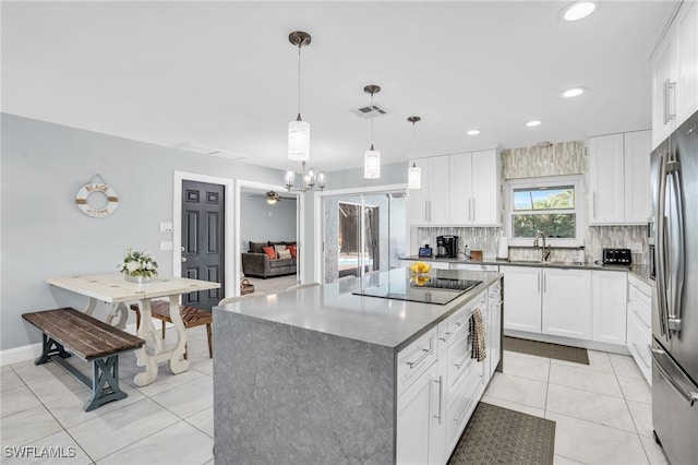 kitchen featuring stainless steel fridge with ice dispenser, a kitchen island, pendant lighting, black electric stovetop, and white cabinets