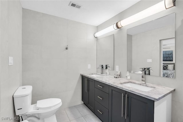 bathroom featuring vanity, toilet, tile patterned flooring, and tile walls