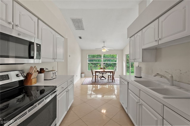 kitchen featuring appliances with stainless steel finishes, sink, light tile patterned floors, ceiling fan, and white cabinets