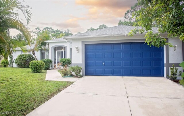 single story home with a garage and a lawn