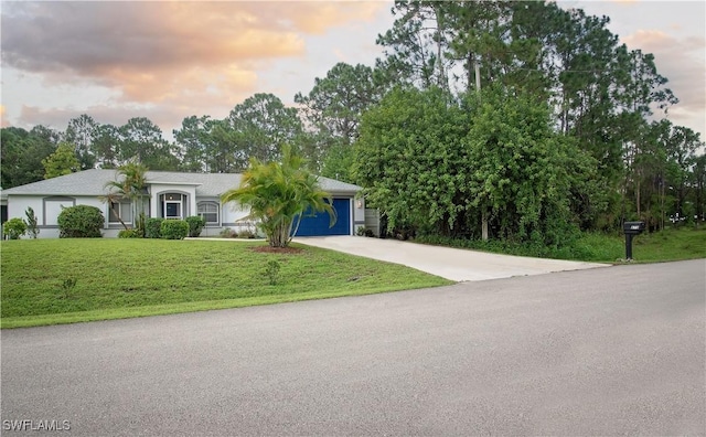 view of front of home with concrete driveway, a front lawn, and an attached garage