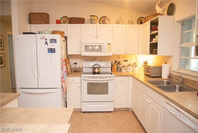 kitchen with white appliances, lofted ceiling, sink, and white cabinets