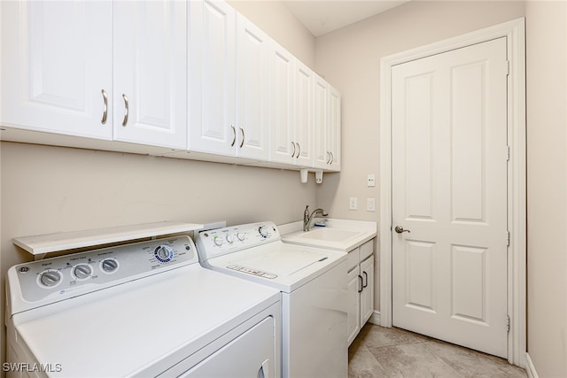 laundry area with light tile patterned flooring, sink, washing machine and clothes dryer, and cabinets