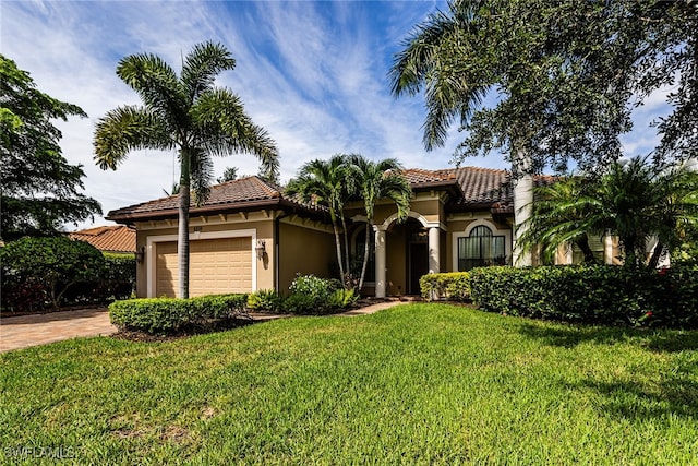 mediterranean / spanish-style home featuring a garage and a front yard