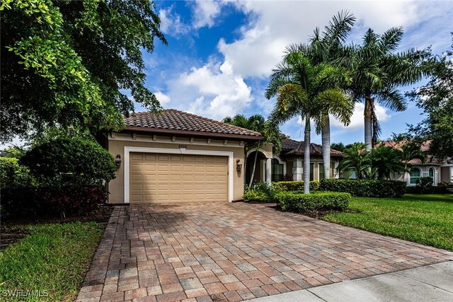 mediterranean / spanish home featuring a garage and a front lawn