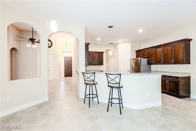 kitchen with ceiling fan, light tile patterned floors, light stone countertops, and stainless steel refrigerator with ice dispenser