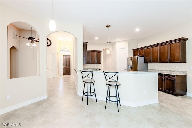 kitchen with a ceiling fan, stainless steel fridge, decorative light fixtures, and dark brown cabinets