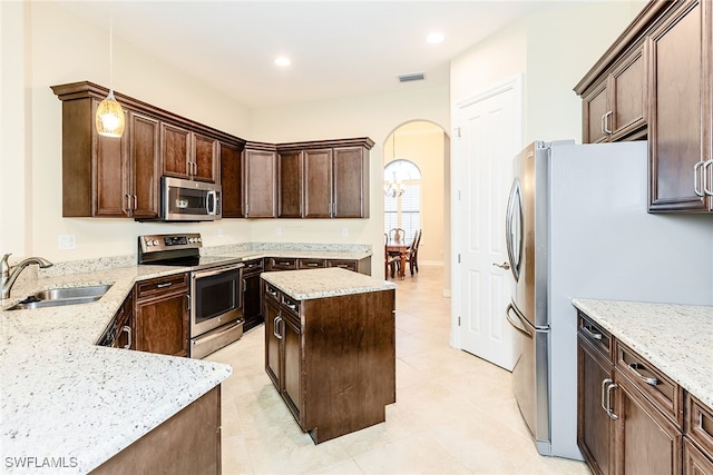 kitchen with sink, decorative light fixtures, appliances with stainless steel finishes, a kitchen island, and light tile patterned floors