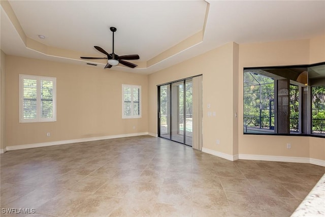unfurnished room with ceiling fan, visible vents, baseboards, and a raised ceiling